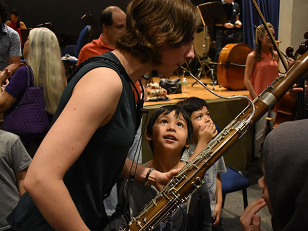 young boy watching an icopr player demonstrate the bassoon